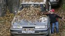 A boy plays with autumn leaves on a parked car in Russia's Siberian city of Krasnoyarsk October 6, 2012. REUTERS/Ilya Naymushin (RUSSIA - Tags: ENVIRONMENT TRANSPORT SOCIETY) Published: Říj. 6, 2012, 10:51 dop.