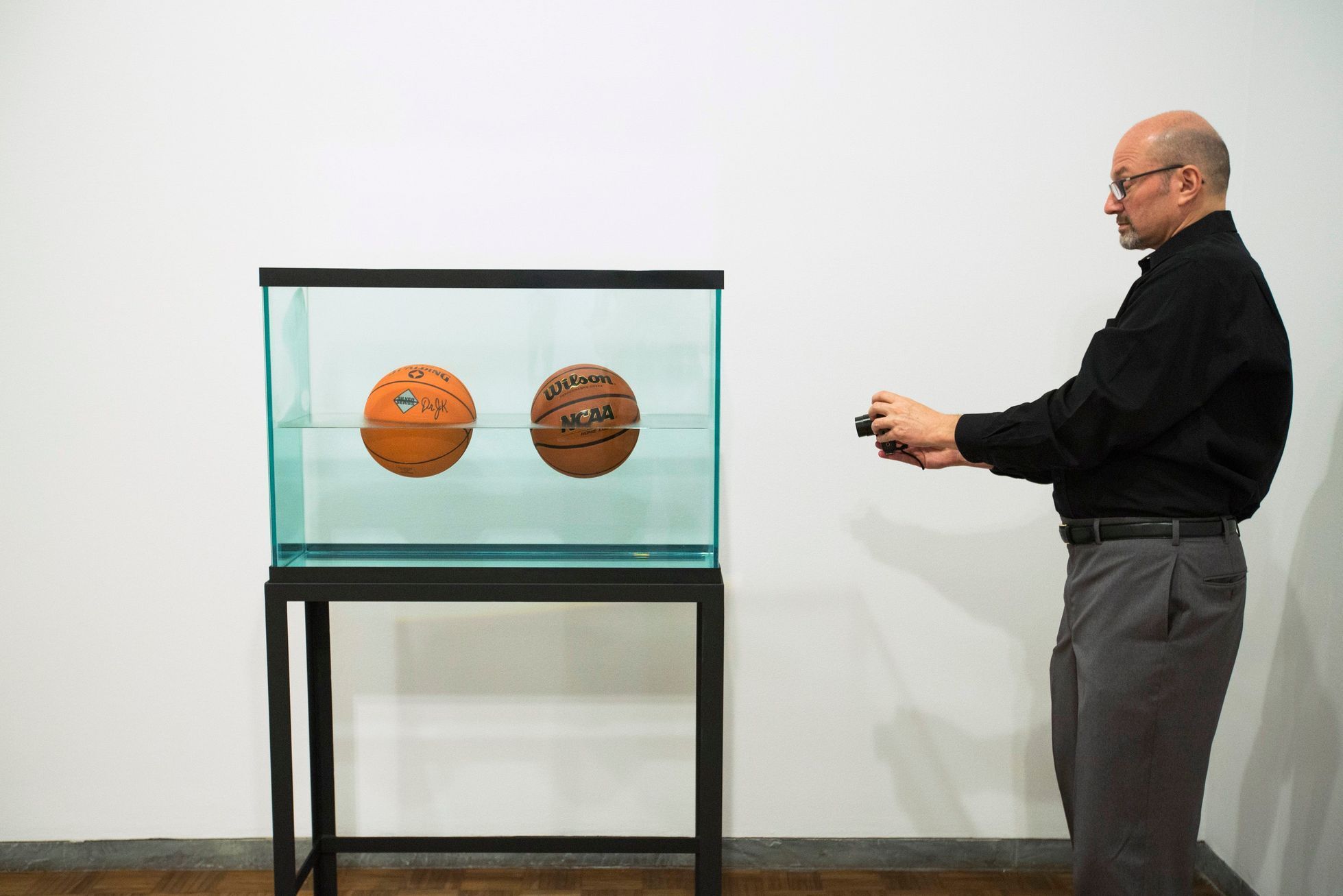 A man photographs the sculpture Two Ball 50/50 Tank during a media preview before the opening of a Jeff Koons retrospective at the Whitney Museum of American Art in New York