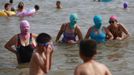 Women, wearing nylon masks, stand in the water during their visit to a beach in Qingdao, Shandong province July 6, 2012. The mask, which was invented by a woman about seven years ago, is used to block the sun's rays. The mask is under mass production and is on sale at local swimwear stores. REUTERS/Aly Song (CHINA - Tags: SOCIETY ENVIRONMENT TRAVEL) Published: Čec. 6, 2012, 4:17 odp.