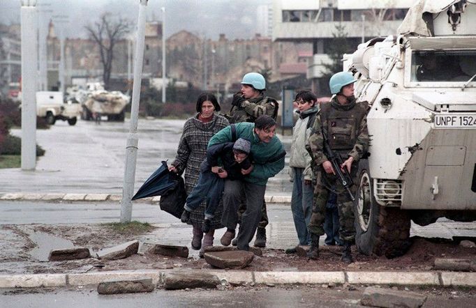 Civilisté se ukrývají před ostřelováním srbských snajperů za obrněným transportérem mírových jednotek UNPROFOR. Sarajevo, rok 1993.