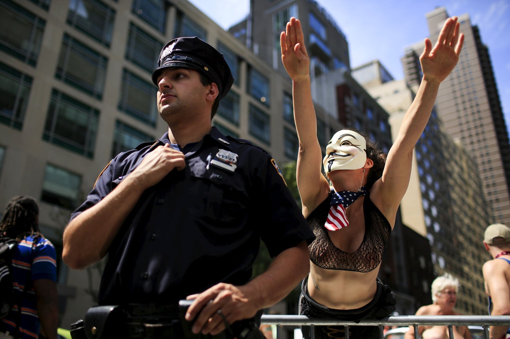 A woman gestures next to a New York Police Officer while she awaits the start of a topless march in New York