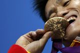 Čínský vzpěrač Siao-ťün Lu s radostí kouše do zlaté medaile, kterou vyhrál v kategorii do 77 kg.