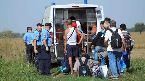 Chorvartší policisté nakládají od aut běžence, kteří se pěšky vydali směrem ke Slovinsku. Premiér oznámil, že jim nebude bránit v cestě na Západ.