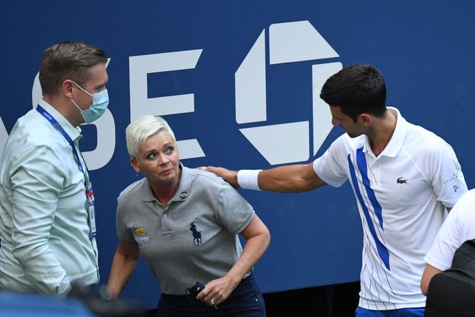 Sep 6, 2020; Flushing Meadows, New York, USA; Novak Djokovic of Serbia and a tournament official tend to a linesperson who was struck with a ball by Djokovic against Pabl