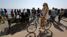 A tourist cycles past hundreds of Afghan immigrants waiting for temporary documents, which allows them to buy tickets for a ferry to Athens