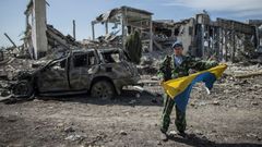 Ukrajina - proruský rebel s ukořistěnou ukrajinskou vlajkou na letišti v Luhansku
