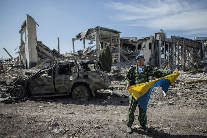 Proruský rebel s ukořietěnou ukrajinskou vlajskou na letišti v Luhansku.