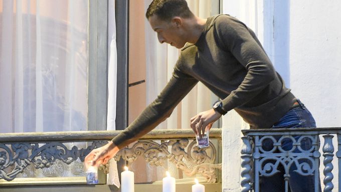 Salahův bratr Mohamed Abdeslam zapaluje na balkonu svého bytu v bruselské čtvrti Molenbeek svíčky za oběti pařížských útoků.