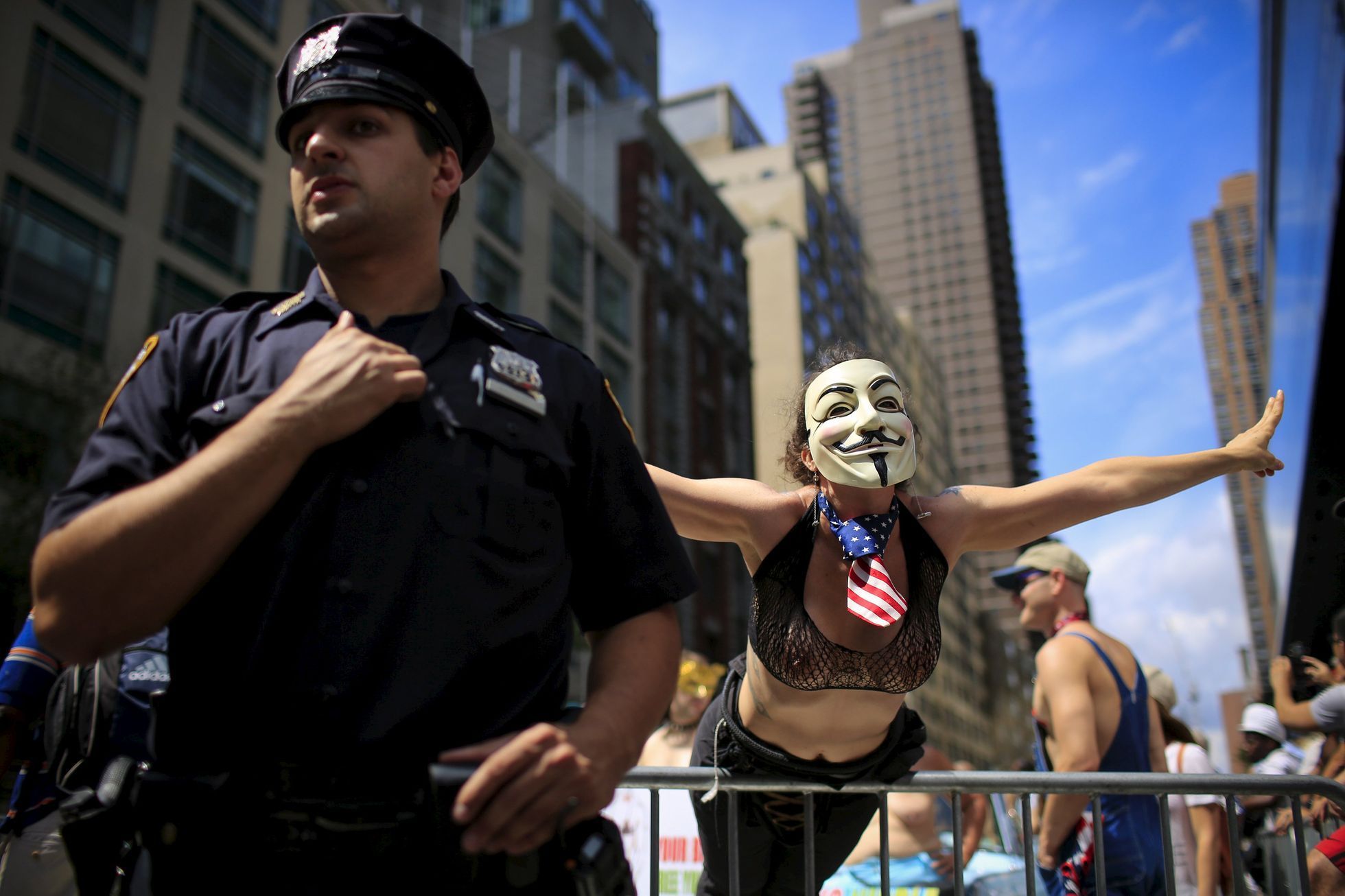 A woman gestures next to a New York Police Officer as she awaits the start of a topless march in New York