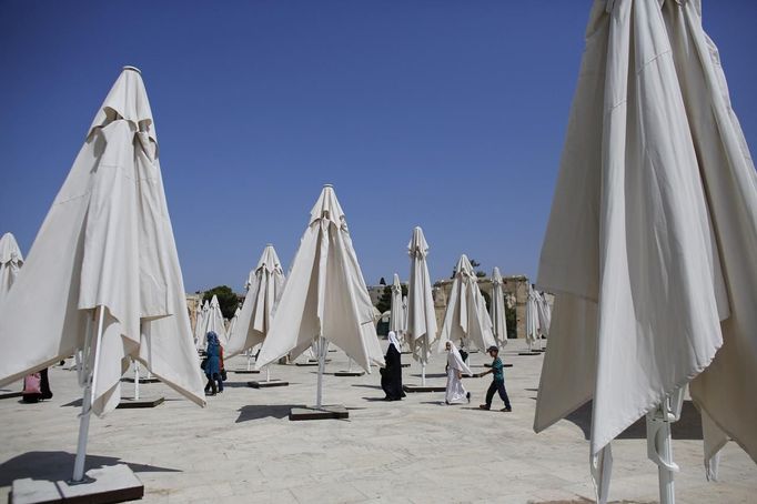 Palestinians walk past parasols set up ahead of the holy month of Ramadan on the compound known to Muslims as "al-Haram al-Sharif" and to Jews as "Temple Mount" in Jerusalem's Old City July 8, 2013. REUTERS/Ammar Awad (JERUSALEM - Tags: RELIGION) Published: Čec. 8, 2013, 1:05 odp.