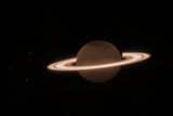 Teleskop Jamese Webba také pořídil na konci června fotografii Saturnu. Planeta vypadá tmavě, protože je zachyceno její blízké infračervené záření - v téhle vlnové délce lze pozorovat, že metan v atmosféře absorbuje sluneční světlo. Jeho prstence ale dál září. Tři tečky nalevo od Saturnu jsou jeho měsíce.
