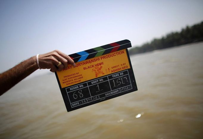 A member of a film crew holds a clapper board during the shooting of Bollywood film 'Black Home' at a beach on the outskirts of Mumbai April 26, 2013. Indian cinema marks 100 years since Dhundiraj Govind Phalke's black-and-white silent film "Raja Harishchandra" (King Harishchandra) held audiences spellbound at its first public screening on May 3, 1913, in Mumbai. Indian cinema, with its subset of Bollywood for Hindi-language films, is now a billion-dollar industry that makes more than a thousand films a year in several languages. It is worth 112.4 billion rupees (over $2 billion) and leads the world in terms of films produced and tickets sold. Picture taken April 26, 2013. REUTERS/Danish Siddiqui (INDIA - Tags: ENTERTAINMENT SOCIETY TPX IMAGES OF THE DAY) ATTENTION EDITORS: PICTURE 1 20 FOR PACKAGE 'BEHIND SCENES BOLLYWOOD'. SEARCH 'BEHIND BOLLYWOOD' FOR ALL Published: Kvě. 2, 2013, 10 odp.