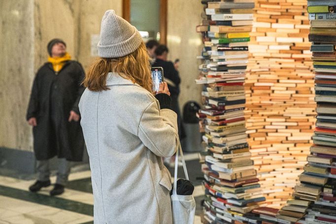 Městská knihovna v Praze a turisté čekající na fotku se sloupem z knih, tzv. Idiomem.