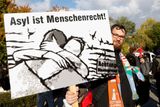 Účastník sobotního shromáždění drží v ruce nápis "Azyl je lidské právo".