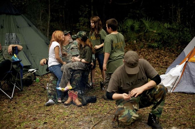 Members of the North Florida Survival Group, including leader Jim Foster (2L) relax in their camp as they take a short break from performing land navigation and enemy contact drills during a field training exercise in Old Town, Florida, December 8, 2012. The group trains children and adults alike to handle weapons and survive in the wild. The group passionately supports the right of U.S. citizens to bear arms and its website states that it aims to teach "patriots to survive in order to protect and defend our Constitution against all enemy threats". Picture taken December 8, 2013. REUTERS/Brian Blanco (UNITED STATES - Tags: SOCIETY POLITICS) ATTENTION EDITORS: PICTURE 17 OF 20 FOR PACKAGE 'TRAINING CHILD SURVIVALISTS' SEARCH 'FLORIDA SURVIVAL' FOR ALL IMAGES Published: Úno. 22, 2013, 1:01 odp.