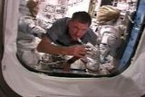 Astronaut Joe Tanner pije zatímco "proplouvá" kolem skafandrů během přípravy na úterní "vesmírnou procházku"