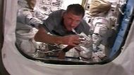 Astronaut Joe Tanner pije zatímco "proplouvá" kolem skafandrů během přípravy na úterní "vesmírnou procházku"
