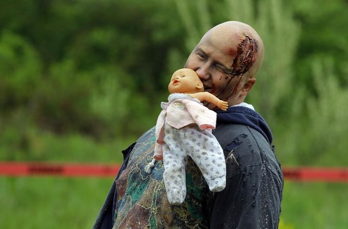 A zombie holds a doll in his mouth on the "Run for Your Lives" 5K obstacle course race in Amesbury, Massachusetts May 5, 2012. Runners face man-made and natural obstacles on the course, while being chased by zombies, who try to take "health" flags off the runners belts. REUTERS/Brian Snyder (UNITED STATES - Tags: SPORT SOCIETY) Published: Kvě. 5, 2012, 11:16 odp.