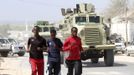 Somali athletes run in front of a convoy of African Union Mission in Somalia (AMISOM) Armoured Personnel Carriers (APC) along a street as they train during preparations for the 2012 London Olympic Games in Somalia's capital Mogadishu in this March 14, 2012 file photo. Training in a bullet-riddled stadium where the remains of a rocket propelled grenade lies discarded on the track's edge counts as progress for Somali Olympic hopeful Mohamed Hassan Mohamed. A year ago, Mogadishu's Konis stadium was a base for Islamist militants and a work out meant at times running through the streets, dodging gun-fire and mortar shells in one of the world's most dangerous cities. Picture taken March 14, 2012. To match OLY-SOMALIA-HOPES/ REUTERS/Feisal Omar/Files (SOMALIA - Tags: SPORT ATHLETICS SOCIETY OLYMPICS) Published: Čer. 11, 2012, 7:16 dop.