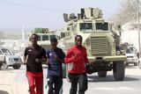 Není sám, do koho chudé Somálsko vkládá své olympijské naděje. Spolu s Mohamedem (vpravo) se na olympiádu připravují další dva atleti. Jeden se jmenuje Abdullah Kuulow (uprostřed), jméno dalšího agentura neuvádí. Páteří jejich přípravy je běhání ulicemi somálské metropole Mogadišo. V současnosti experti tohle město považují za nejnebezpečnější na světě. A to kvůli ozbrojeným milicím, které ve městě operují už řadu let. Stigma občanské války je v Somálsku stále přítomné. Na fotografii je za běžícími atlety vidět obrněné transportéry Africké unie AMISOM, která se snaží v této zemi udržovat křehký klid zbraní.