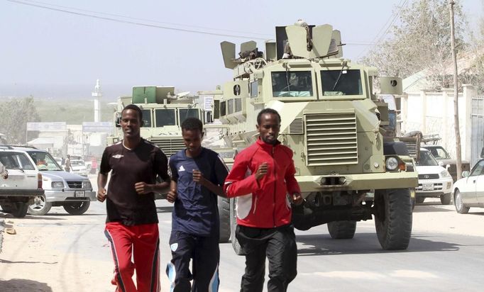 Somali athletes run in front of a convoy of African Union Mission in Somalia (AMISOM) Armoured Personnel Carriers (APC) along a street as they train during preparations for the 2012 London Olympic Games in Somalia's capital Mogadishu in this March 14, 2012 file photo. Training in a bullet-riddled stadium where the remains of a rocket propelled grenade lies discarded on the track's edge counts as progress for Somali Olympic hopeful Mohamed Hassan Mohamed. A year ago, Mogadishu's Konis stadium was a base for Islamist militants and a work out meant at times running through the streets, dodging gun-fire and mortar shells in one of the world's most dangerous cities. Picture taken March 14, 2012. To match OLY-SOMALIA-HOPES/ REUTERS/Feisal Omar/Files (SOMALIA - Tags: SPORT ATHLETICS SOCIETY OLYMPICS) Published: Čer. 11, 2012, 7:16 dop.