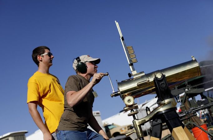 Matt McLuckie watches as Thomas Young fires a Colt 1877 Bulldog Gatling gun during the Big Sandy Shoot in Mohave County, Arizona March 22, 2013. The Big Sandy Shoot is the largest organized machine gun shoot in the United States attended by shooters from around the country. Vintage and replica style machine guns and cannons are some of the weapons displayed during the event. Picture taken March 22, 2013. REUTERS/Joshua Lott (UNITED STATES - Tags: SOCIETY) Published: Bře. 25, 2013, 3:34 odp.