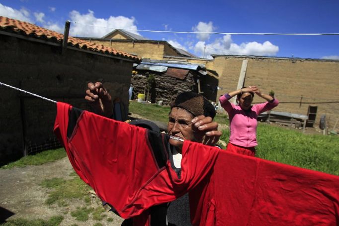 Marathon runner Gladys Tejeda (rear), the first Peruvian athlete who qualified for the 2012 London Olympic Games, looks at her mother Marcelina Pucuhuaranga as she hangs up clothes at her home in the Andean province of Junin May 14, 2012. A private company will take Pucuhuaranga, 69, to London as part of the "Thank you Mom" program. For Pucuhuaranga, who received her first passport, it will be the first time travelling out of Peru. The program will take about 120 mothers of different athletes around the world to attend the games. Tejeda, the youngest of nine children, returned to her hometown to visit her mother and to focus on training where she will run more than 20 km every day in the highlands (over 4,105 meters above sea level). Picture taken May 14, 2012. REUTERS/Pilar Olivares(PERU - Tags: SPORT ATHLETICS OLYMPICS) Published: Kvě. 17, 2012, 6:40 odp.