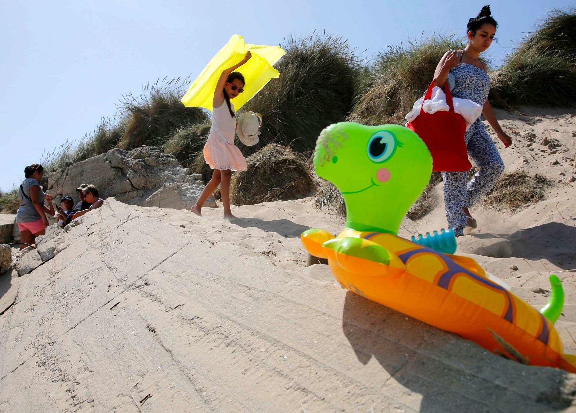 French bathers walk over the remains of a concrete wall on the former Utah Beach D-Day landing zone near La Madeleine