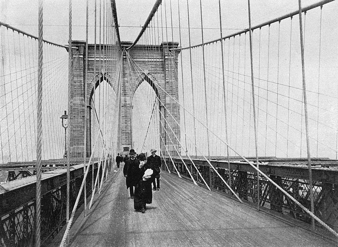 Lidé na pěší promenádě na Brooklynském mostu v New Yorku na fotografii z roku 1898.