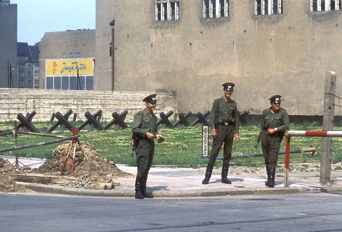 Tři pohraničníci Národní lidové armády NDR hlídkují u spojeneckého kontrolního stanoviště Checkpoint Charlie na Friedrichstraße v Berlíně, srpen 1961.