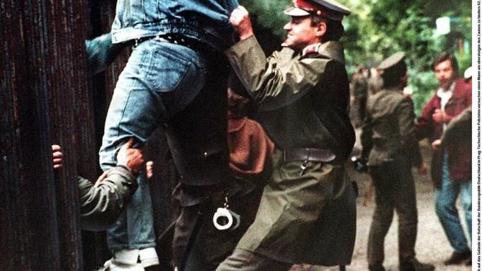 Takto to vypadalo 2. října 1989 u německé ambasády v Praze: Fleischmann leze přes plot, esenbák se mu v tom marně snaží zabránit