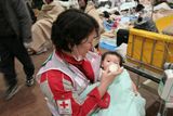 Členka japonského Červeného kříže se stará o dítě.