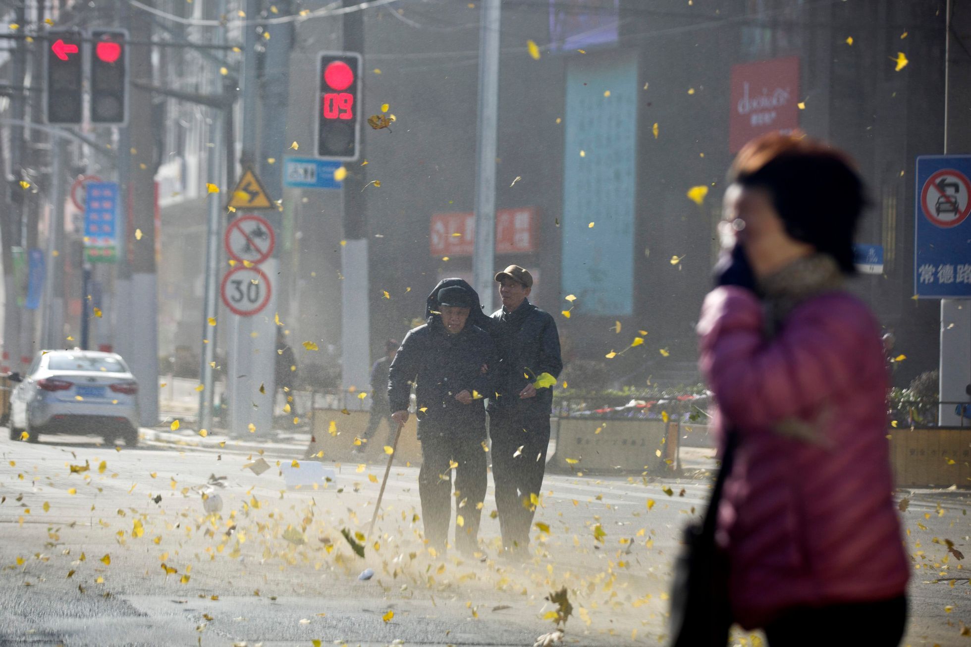 People walk along a street on a windy day in central Shanghai
