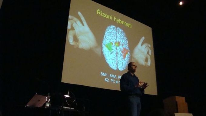 Neurolog Robert Jech z Univerzity Karlovy při přednášce v rámci Týdne vědy ukazuje na snímku svého mozku, které jeho části pracují, když hýbe prsty.