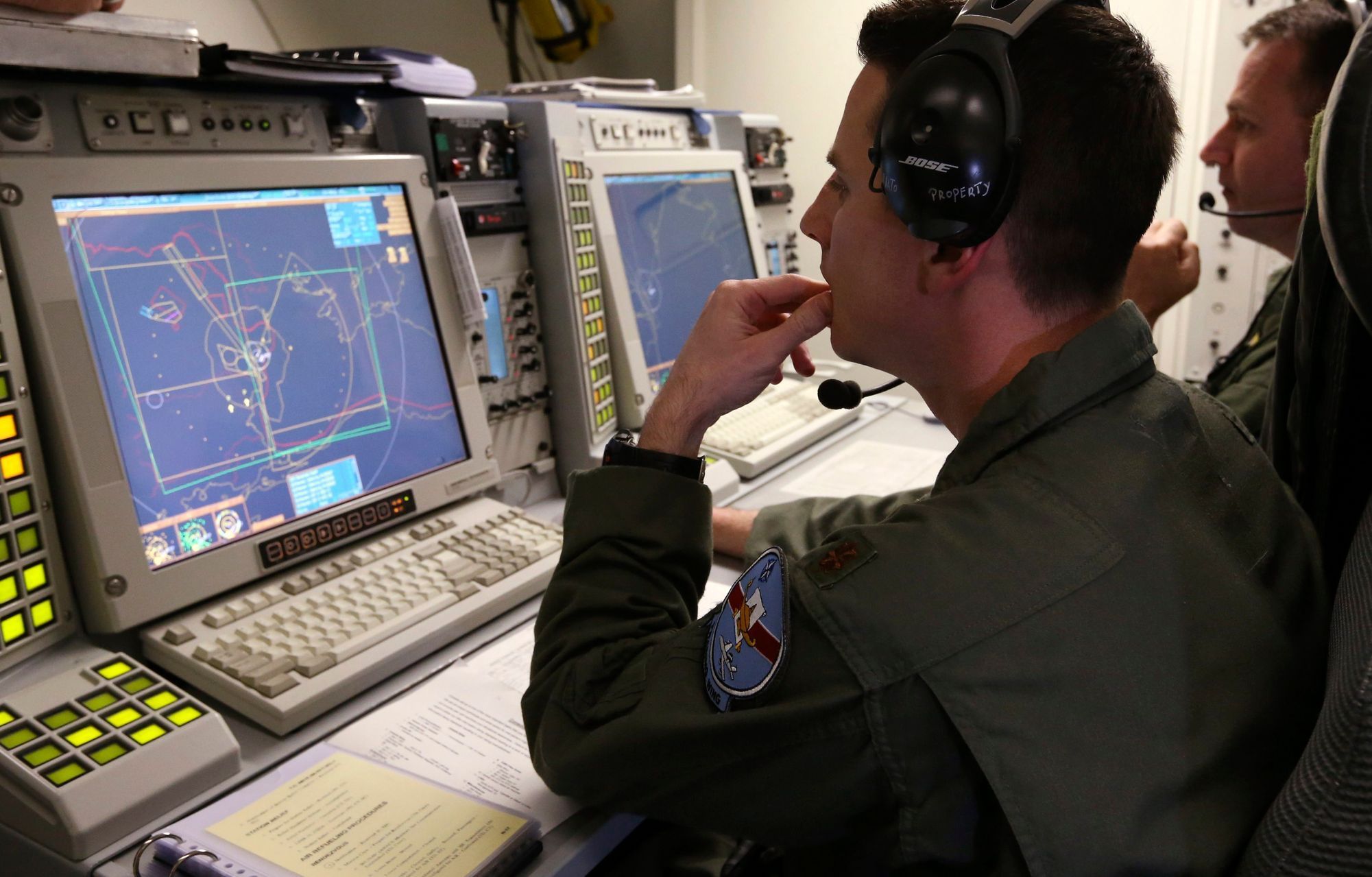 Controllers sit at screens aboard a NATO AWACS aircraft during a surveillance flight over Romania