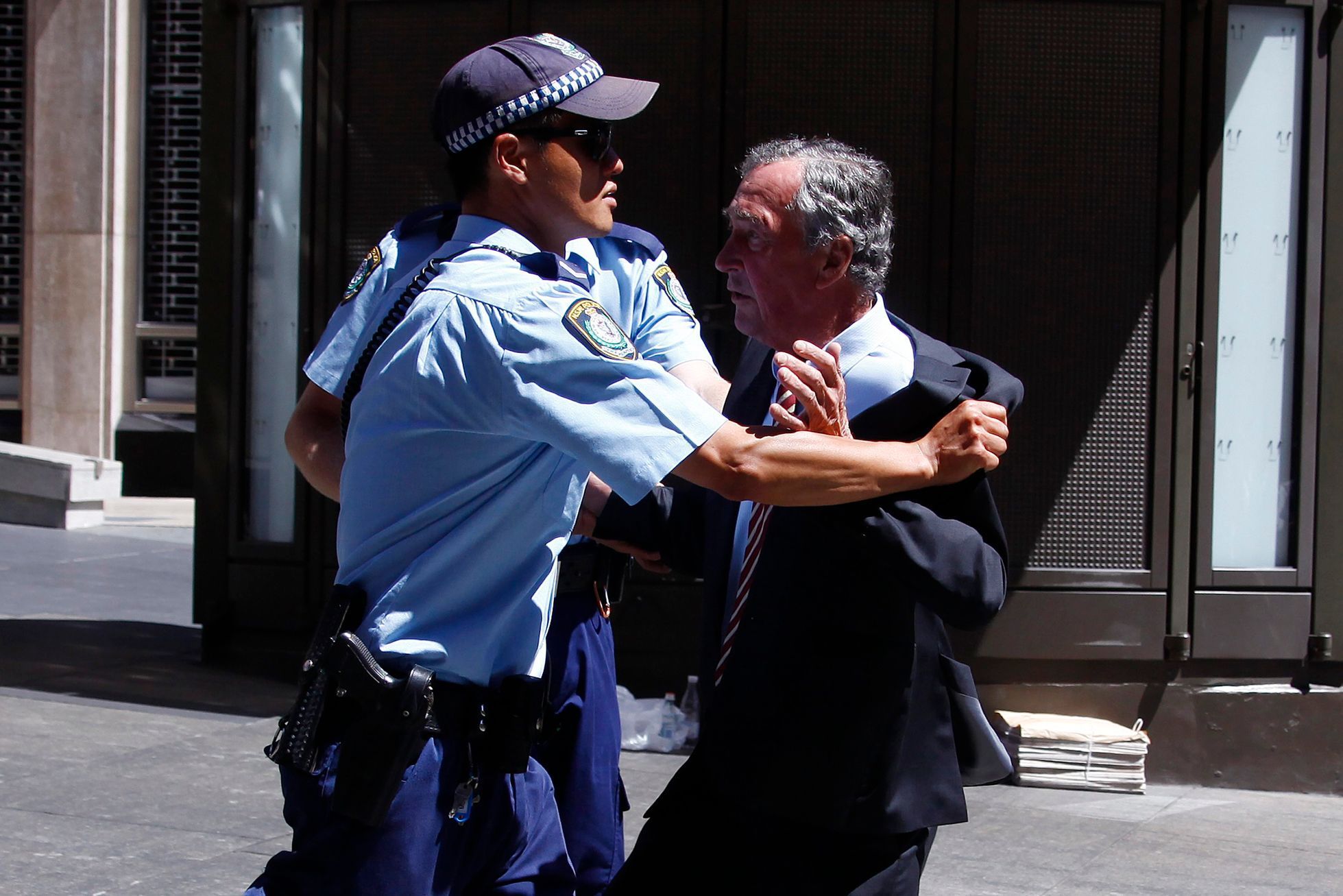 Policista drží muže, který se pokoušel dostat ke kavárně Lindt, kde ozbrojenec zadržuje rukojmí.