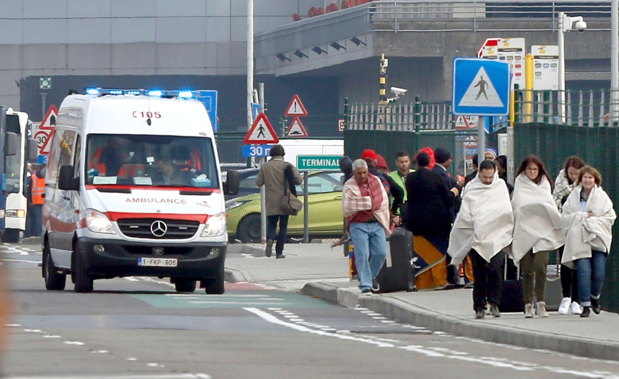 People wrapped in blankets leave the scene of explosions at  Zaventem airport near Brussels, Belgium