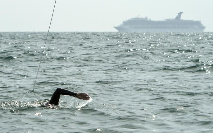 A cruise ship passes in the distance as Diana Nyad trains off Key West, Florida, August 13, 2012. Nyad, who turns 63 on August 22nd, plans to begin her fourth attempt to swim from Havana, Cuba, to the Florida Keys on Sunday, August 19, 2012. She says that severe jellyfish stings thwarted her third attempt and plans to wear the new suit during night time swimming. Photo taken August 13, 2012. REUTERS/Presley Adamson/Florida Keys News Bureau/Handout (UNITED STATES - Tags: SOCIETY) NO SALES. NO ARCHIVES. FOR EDITORIAL USE ONLY. NOT FOR SALE FOR MARKETING OR ADVERTISING CAMPAIGNS. THIS IMAGE HAS BEEN SUPPLIED BY A THIRD PARTY. IT IS DISTRIBUTED, EXACTLY AS RECEIVED BY REUTERS, AS A SERVICE TO CLIENTS Published: Srp. 16, 2012, 9:15 odp.