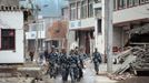 Rescue workers hold shovels as they walk among collapsed houses at Lushan county after Saturday's earthquake, Ya'an, Sichuan province, April 22, 2013. Hundreds of survivors of an earthquake that killed nearly 200 people in southwest China pushed into traffic on a main road on Monday, waving protest signs, demanding help and shouting at police. The Chinese characters on the tent read "Disaster relief". Picture taken April 22, 2013. REUTERS/Stringer (CHINA - Tags: DISASTER SOCIETY) Published: Dub. 23, 2013, 3:18 dop.