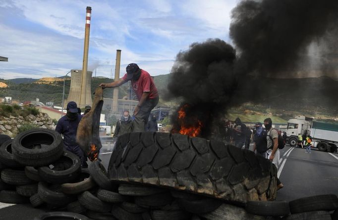 A coal miner burns tires in front of a thermal power station as they block the N-630 road in La Robla, near Leon, northern Spain June 20, 2012. The miners were protesting against the government's proposal to decrease funding for coal production. REUTERS/Eloy Alonso (SPAIN - Tags: BUSINESS EMPLOYMENT POLITICS CIVIL UNREST) Published: Čer. 20, 2012, 12:56 odp.