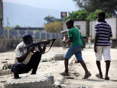 Haitský policista se připravuje střílet na rabující obyvatele.