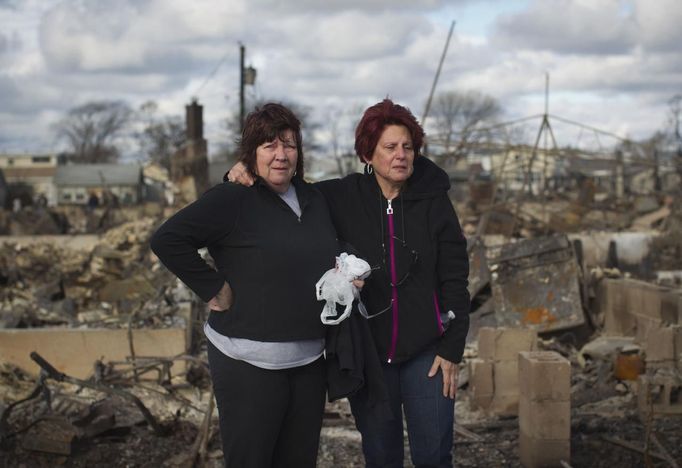 Neighbors Lucille Dwyer (R) and Linda Strong embrace after looking through the wreckage of their homes devastated by fire and the effects of Hurricane Sandy in the Breezy Point section of the Queens borough of New York October 31, 2012. The U.S. Northeast began crawling back to normal on Wednesday after monster storm Sandy crippled transportation, knocked out power for millions and killed at least 45 people in nine states with a massive storm surge and rain that caused epic flooding. REUTERS/Shannon Stapleton (UNITED STATES - Tags: ENVIRONMENT DISASTER) Published: Říj. 31, 2012, 3:46 odp.