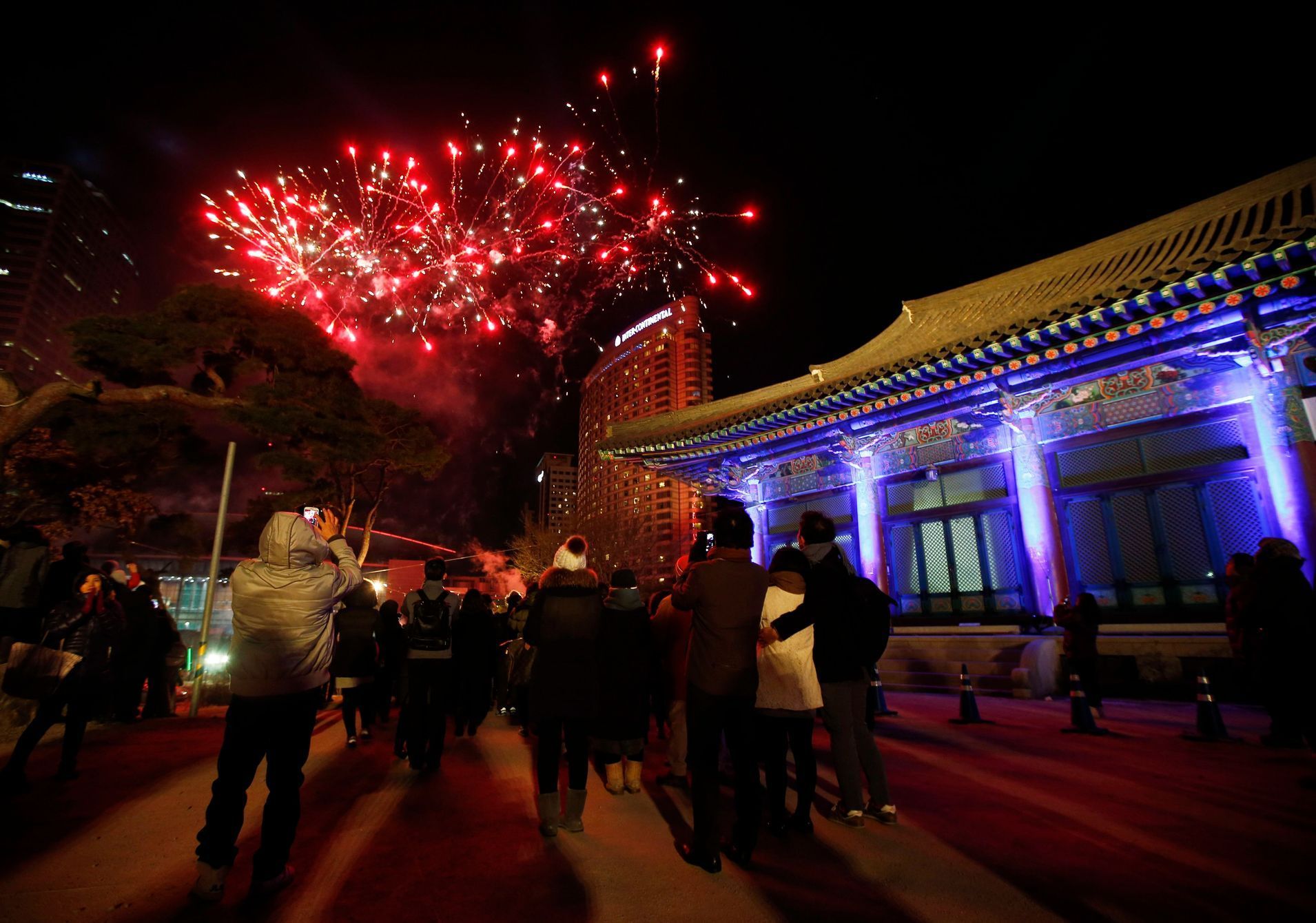 Buddhist believers watch as fireworks go off during a ceremony to celebrate the new year at Bongeun Buddhist temple in Seoul