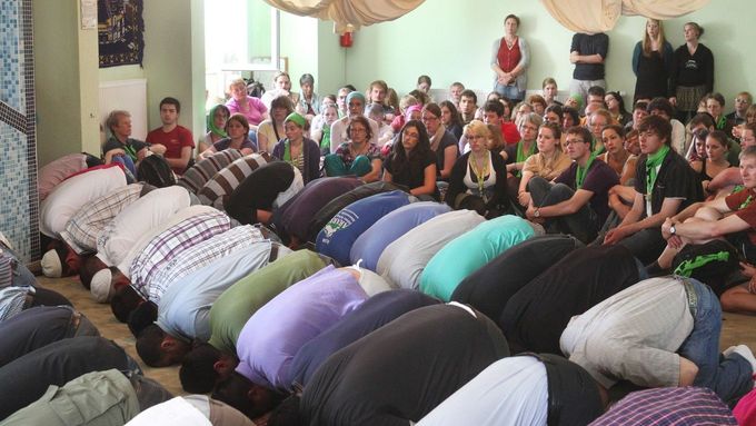 Turečtí muslimové (vpředu) sledovaní německými křesťany (v pozadí) během páteční modlitby v mešitě v Drážďanech, Německo.
