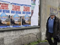 Muž prochází kolem plakátů strany Lid svobody Silvia Berlusconiho v Miláně.