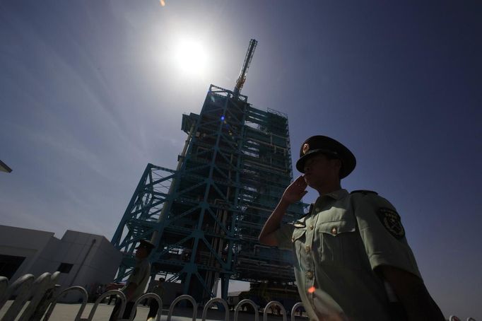 A soldier salutes in front of the launch pad holding the Long March II-F rocket loaded with Shenzhou-9 manned spacecraft, in Jiuquan Satellite Launch Center, Gansu province, June 16, 2012. China will send its first woman into outer space this week, prompting a surge of national pride as the rising power takes its latest step towards putting a space station in orbit within the decade. Liu Yang, a 33-year-old fighter pilot, will join two other astronauts aboard the Shenzhou 9 spacecraft when it lifts off from a remote Gobi Desert launch site on Saturday evening. REUTERS/Jason Lee (CHINA - Tags: SCIENCE TECHNOLOGY MILITARY) Published: Čer. 16, 2012, 4:14 dop.