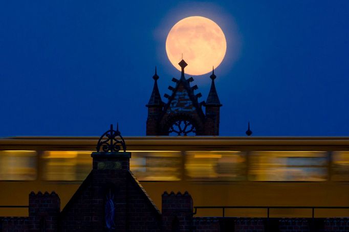 The supermoon rises behind Oberbaum Bridge as a train passes through in Berlin