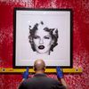 A gallery assistant hangs work depicting Kate Moss at the Banksy: The Unauthorised Retrospective exhibition at Sotheby's S2 Gallery in London