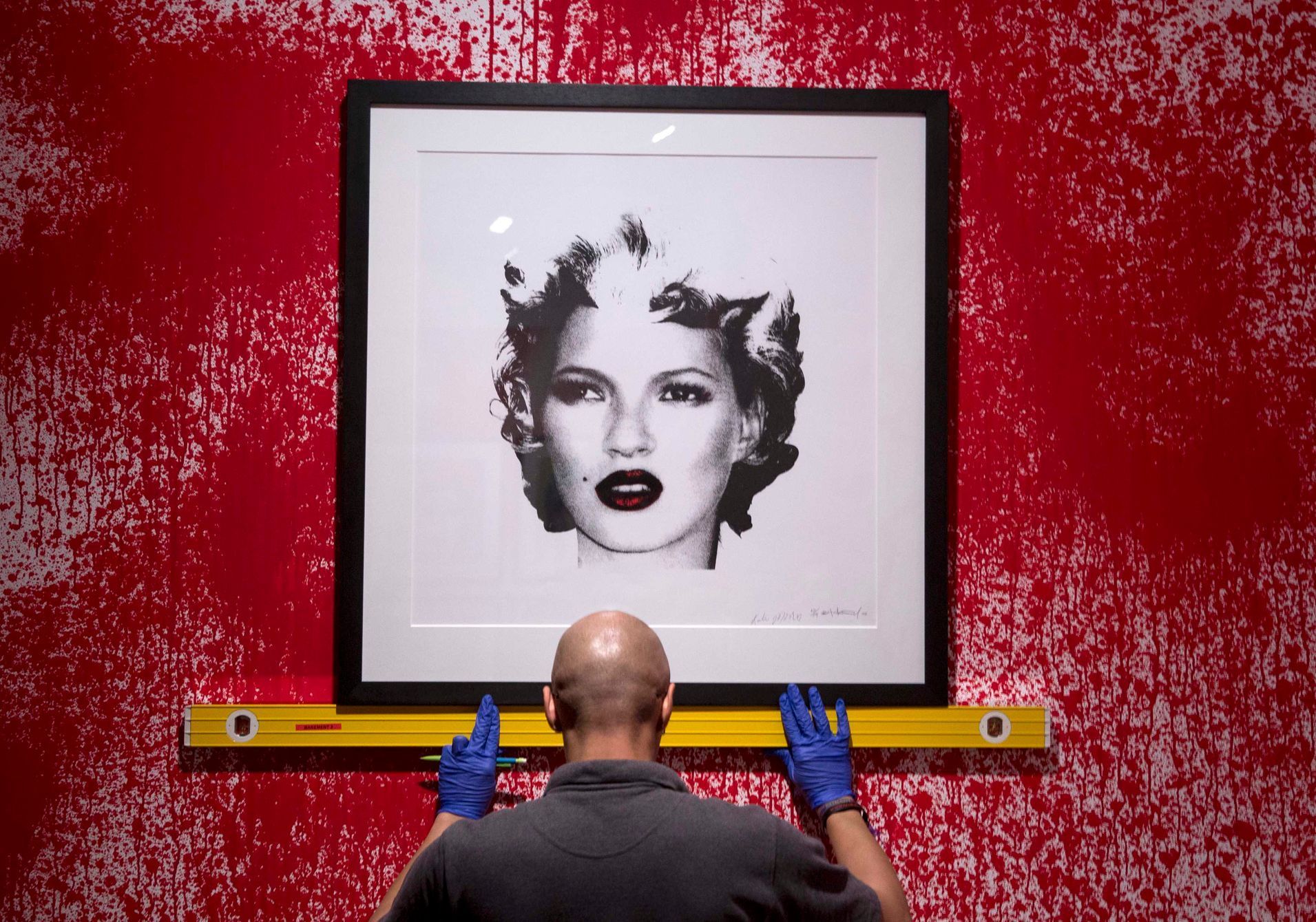 A gallery assistant hangs work depicting Kate Moss at the Banksy: The Unauthorised Retrospective exhibition at Sotheby's S2 Gallery in London