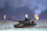 Zničený irácký tank během války v Perském zálivu, v pozadí hořící ropná pole.